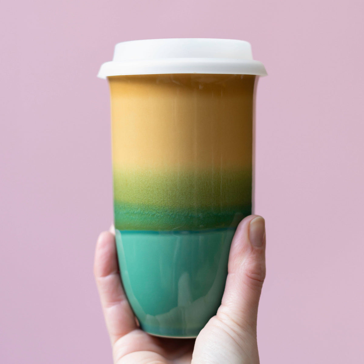 Colorful coffee cup with gradient design held against a pink background