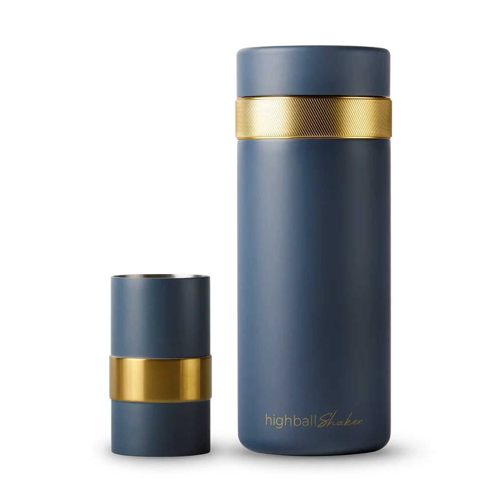 A navy blue highball tumbler with a textured gold band around the neck, shown with its lid removed and standing beside it on a white background.