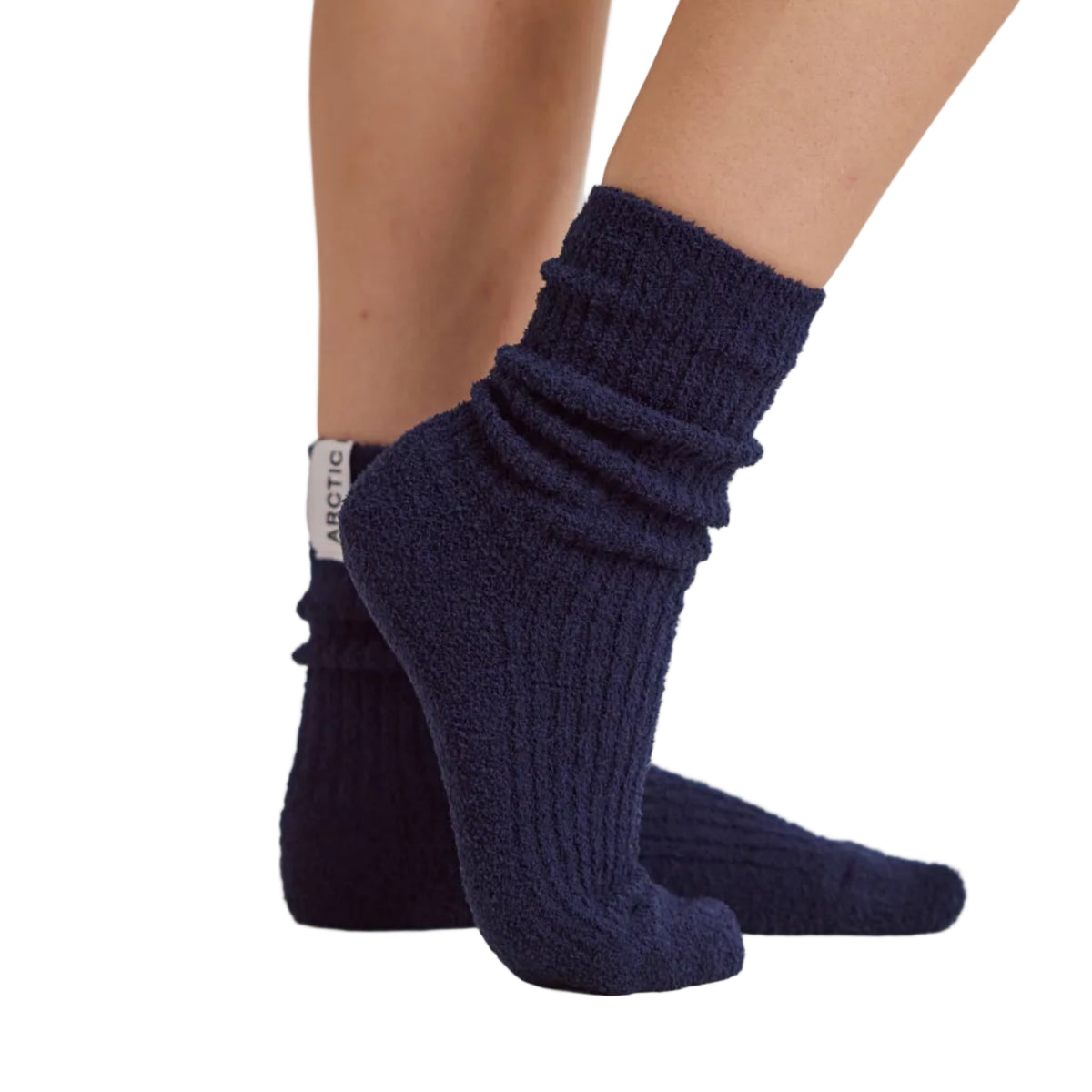 A close-up of a person's feet wearing dark navy blue ribbed knit ankle socks, standing on a white platform.