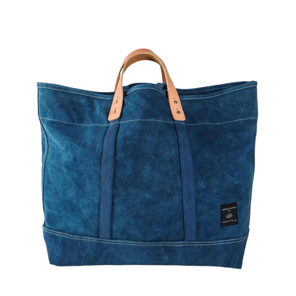 Large indigo canvas tote bag with wide handles, spacious interior, and versatile design for everyday use or travel.
