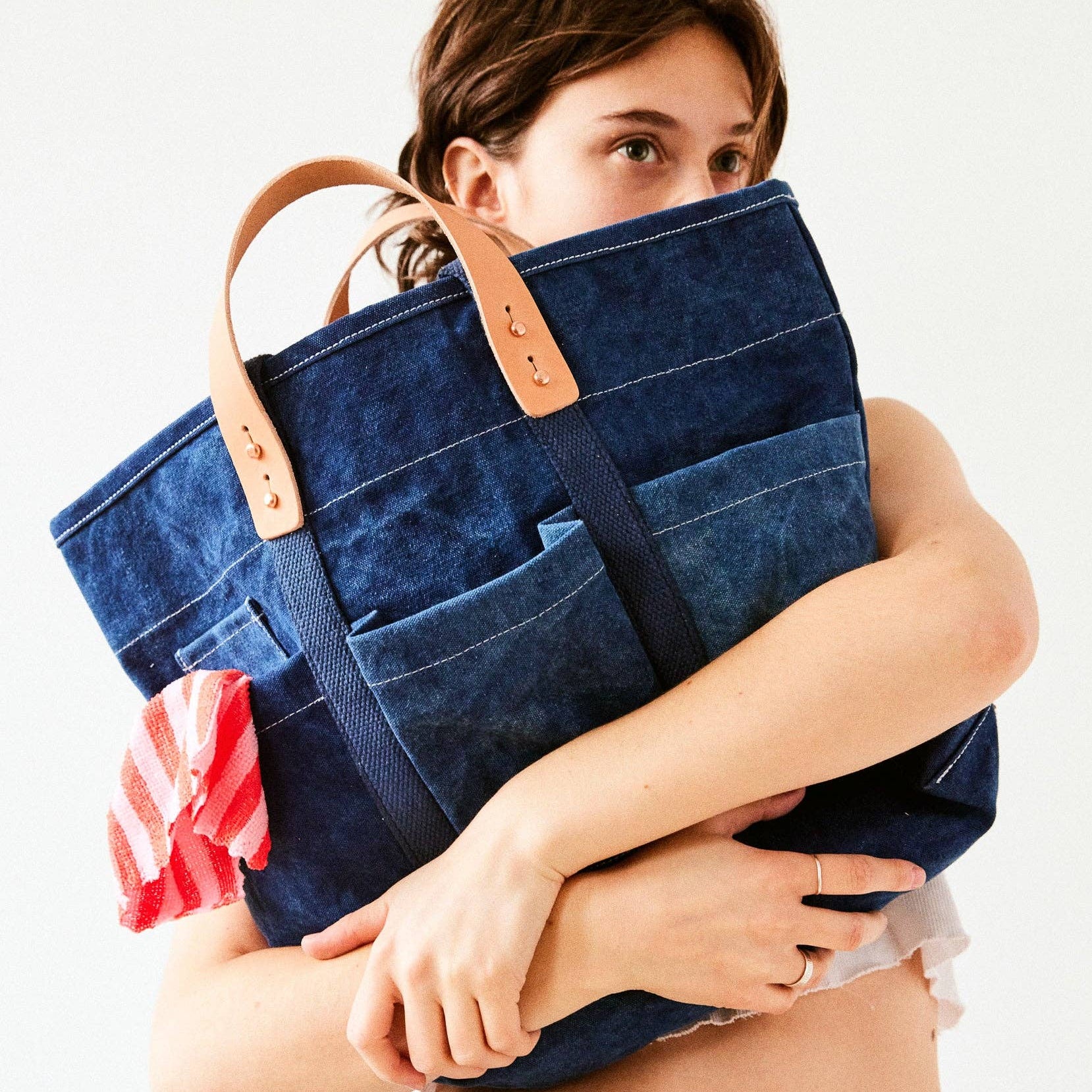 Woman holding a large blue tote bag with a white background