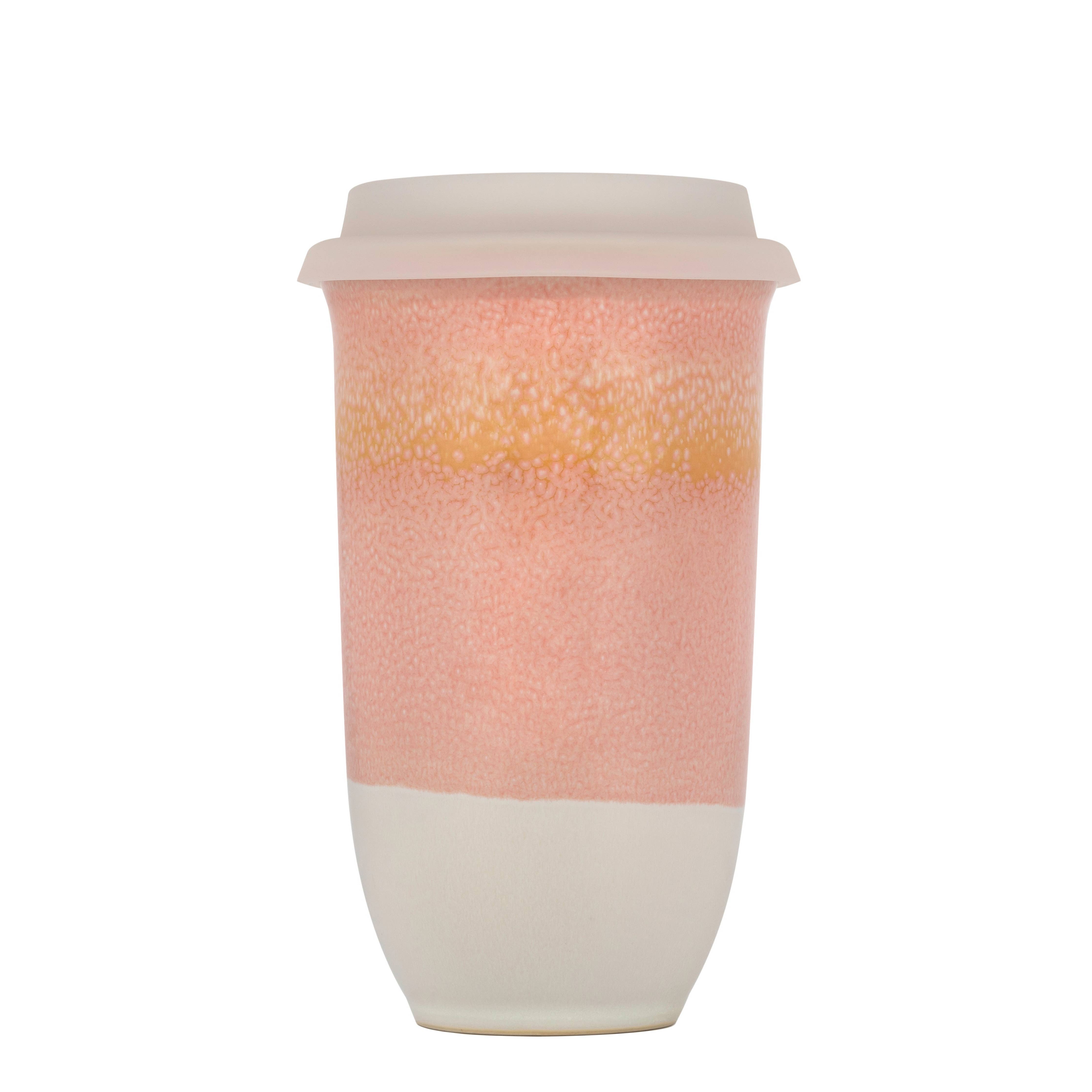 Reusable coffee cup with pink toned gradient design on a white background