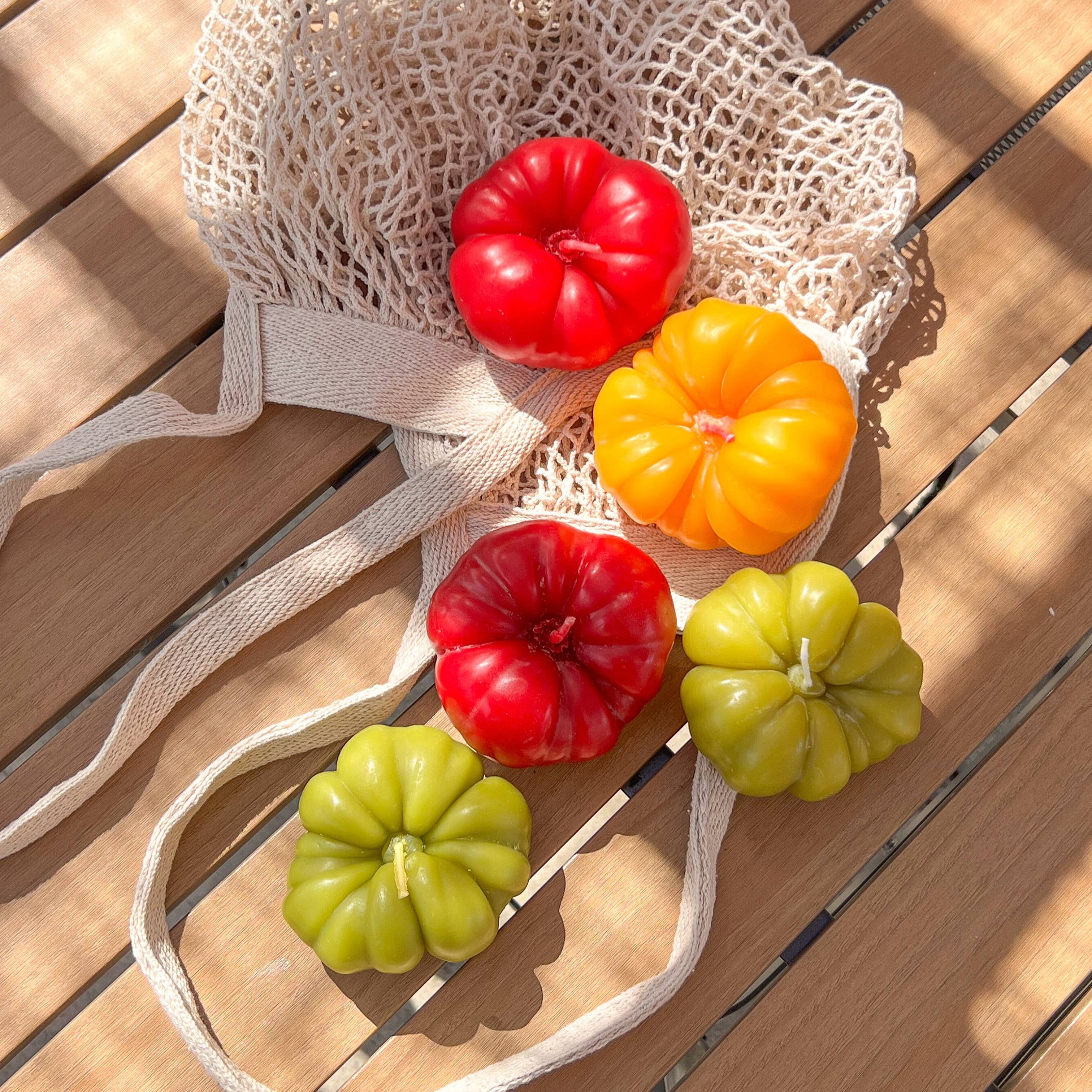 Colorful tomato canndles on a mesh bag on a wooden surface