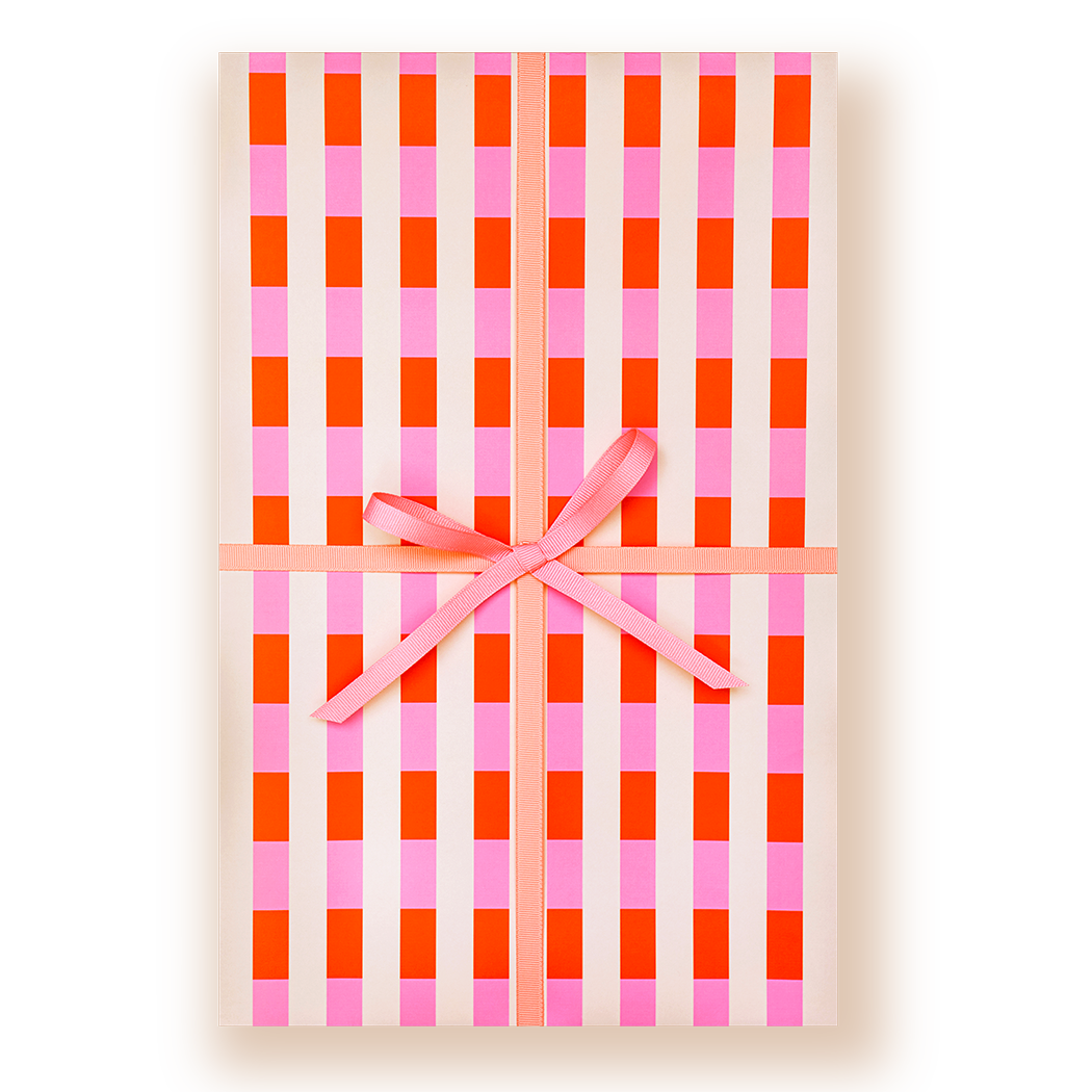 A rectangular gift box wrapped in cream wrapping paper with a pink and orange gingham check pattern, tied with a pink ribbon and bow in the center, on a white background.