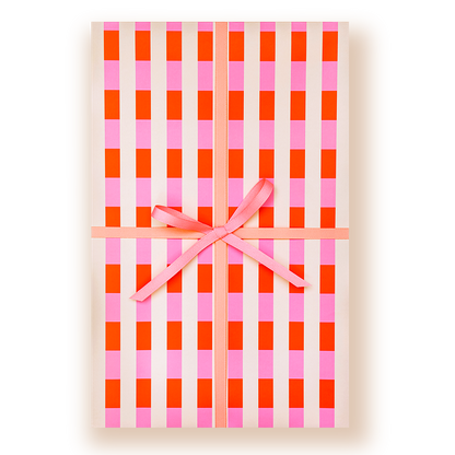 A rectangular gift box wrapped in cream wrapping paper with a pink and orange gingham check pattern, tied with a pink ribbon and bow in the center, on a white background.