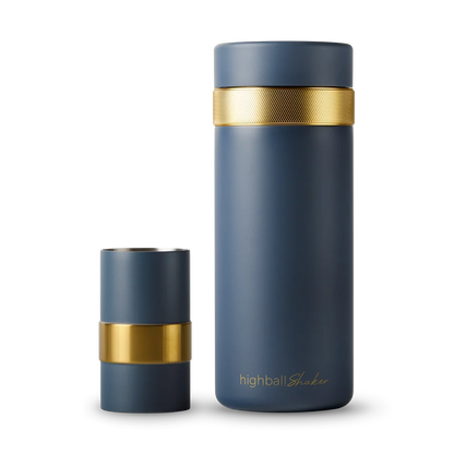 A navy blue highball tumbler with a textured gold band around the neck, shown with its lid removed and standing beside it on a white background.