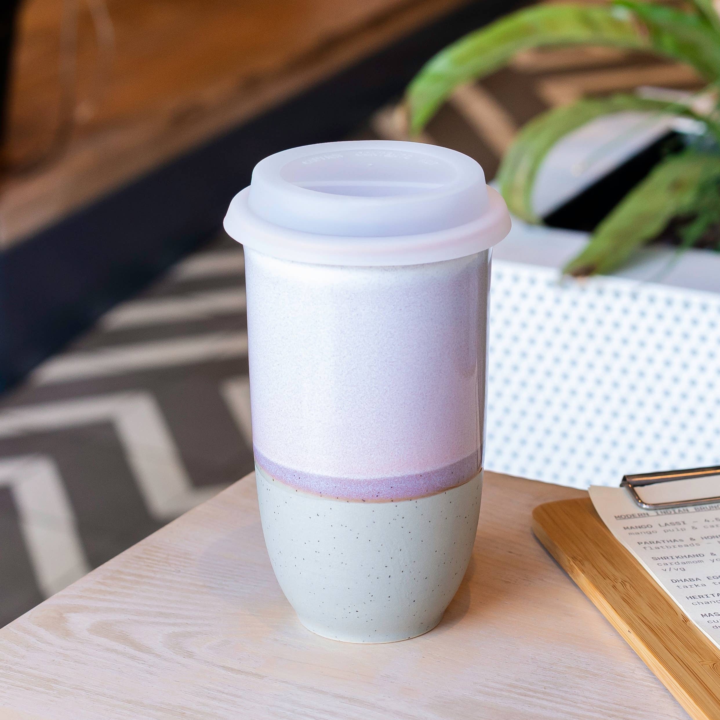 White ceramic tumbler with a purple accent on a wooden table.