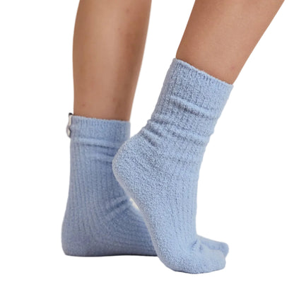 A pair of light blue textured crew socks worn on a person's feet, shown against a white studio background.