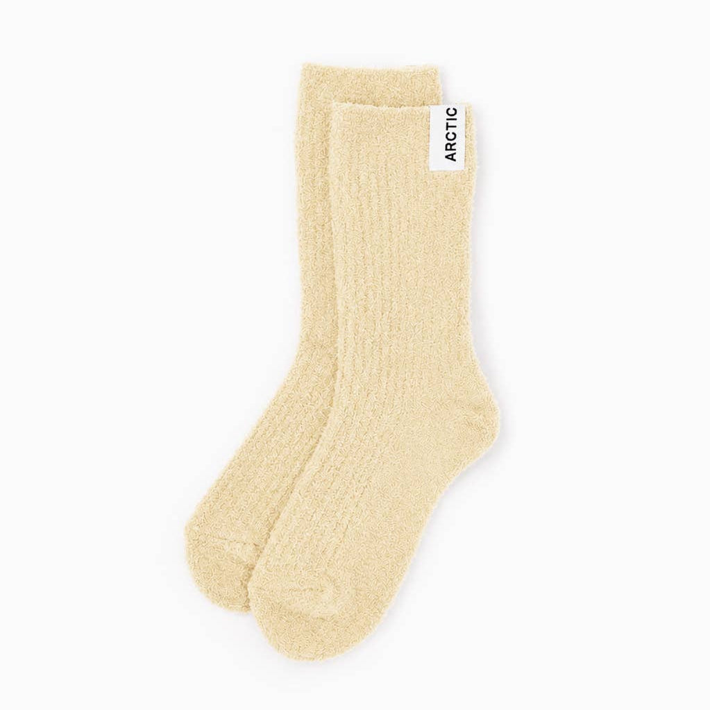 A pair of ribbed ankle socks in a light cream or pale beige color, with a small white brand tag on the cuff that reads 'ARCTIC'. The socks are photographed on a seamless, solid white background.