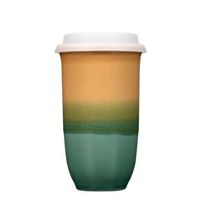 Two-tone green and beige ceramic cup with a white lid on a white background