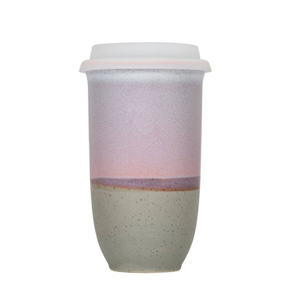 Two-tone ceramic tumbler with a white lid on a white background