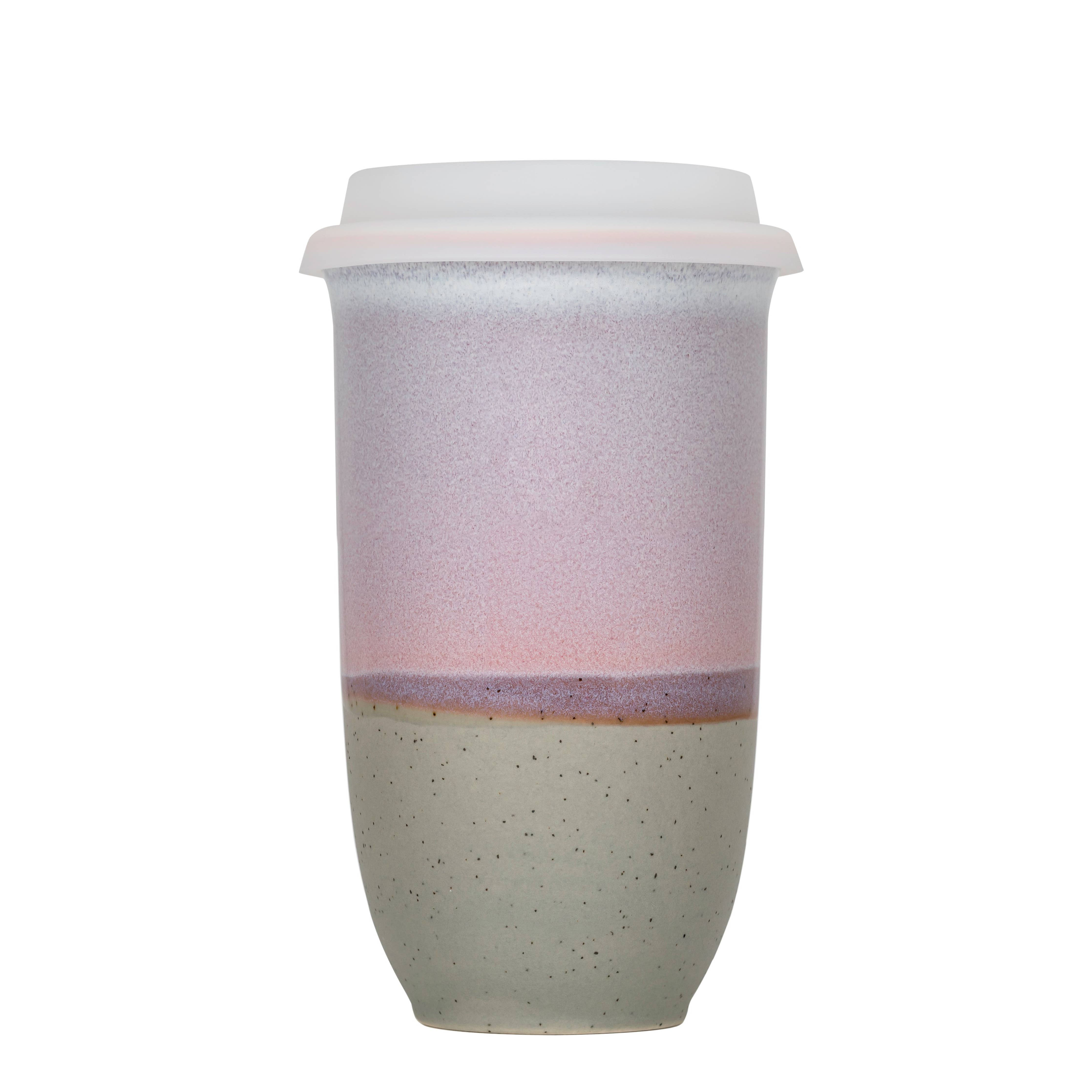 Two-tone ceramic tumbler with a white lid on a white background