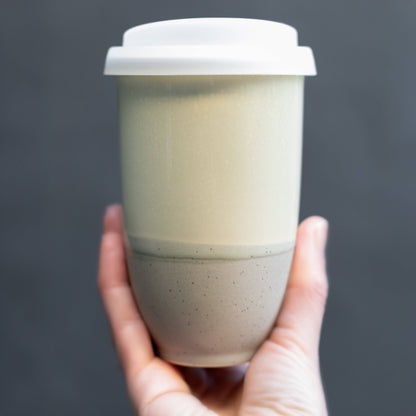 Hand holding a layered coffee cup with a dark gray background