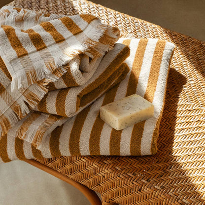 Striped towel and bar of soap on a woven surface