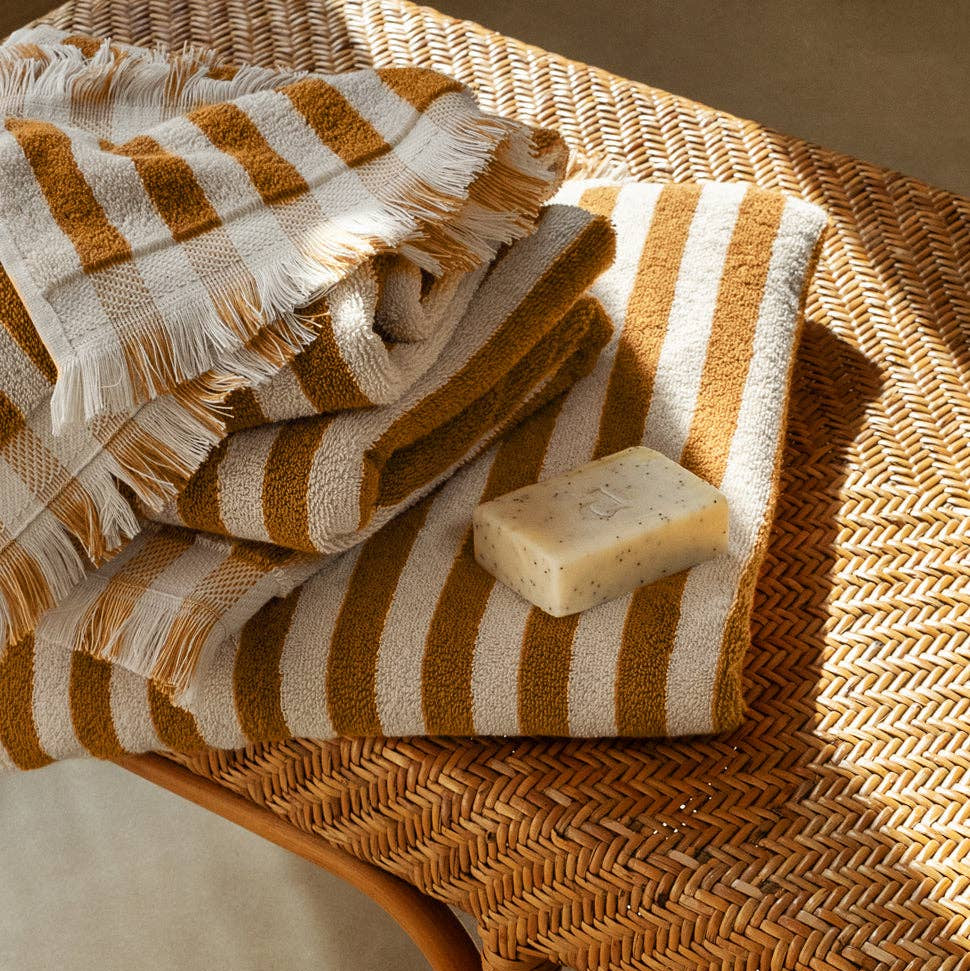 Striped towel and bar of soap on a woven surface