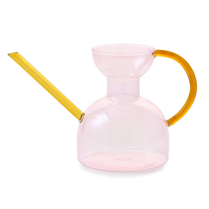 Pink glass pitcher with yellow handle and spout on a white background