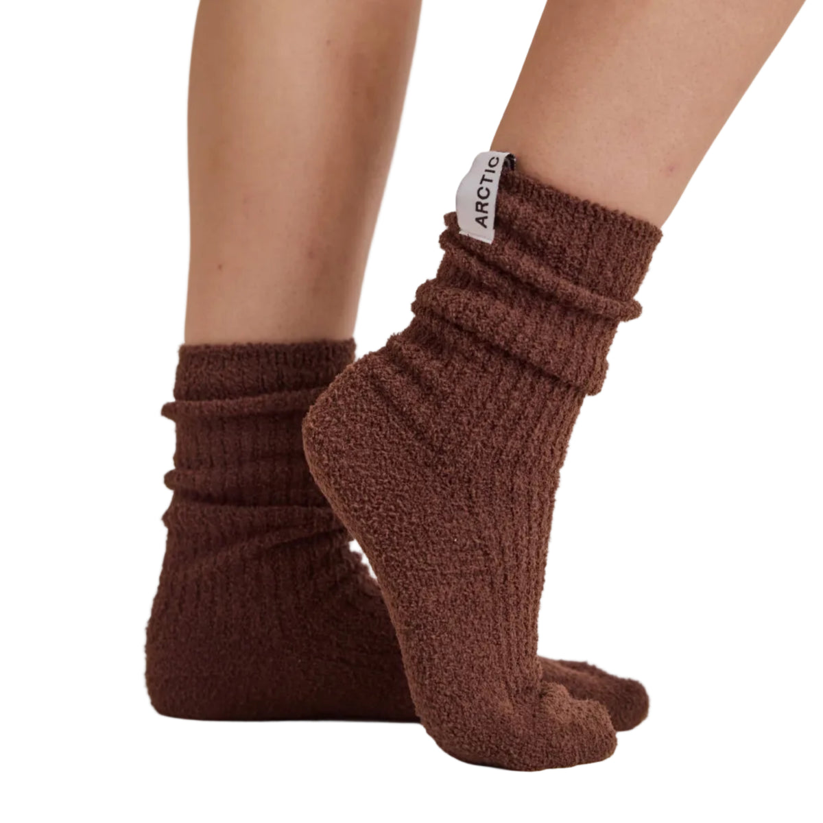 A person wearing brown ribbed knit socks with a small white brand tag reading 'ARCTIC', shown from the calves down against a plain light beige studio background.