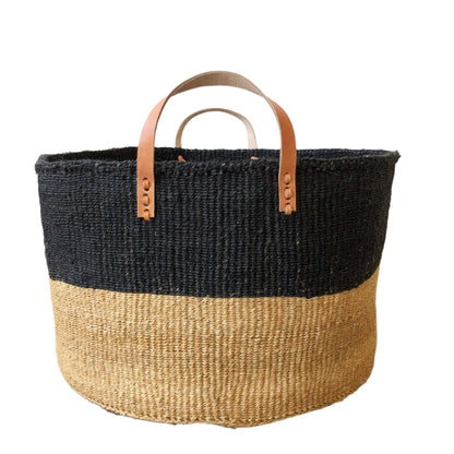 A two toned, neutral and balck, extra large floor basket with leater straps. Perfect for blanket or towel storage.
