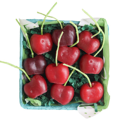 Box of red cherries with green stems on a white background