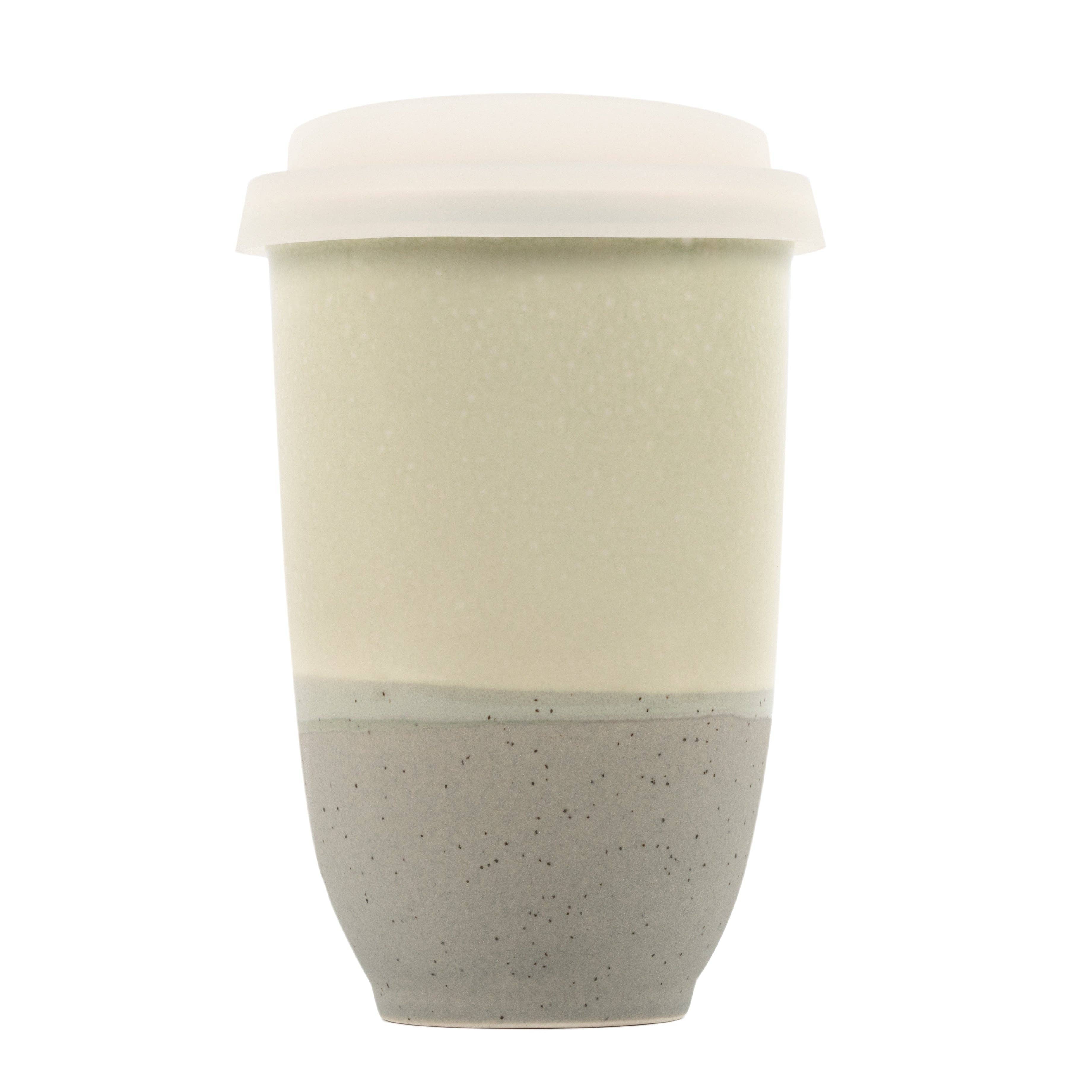 Two-toned ceramic cup with beige top and speckled gray bottom on a white background